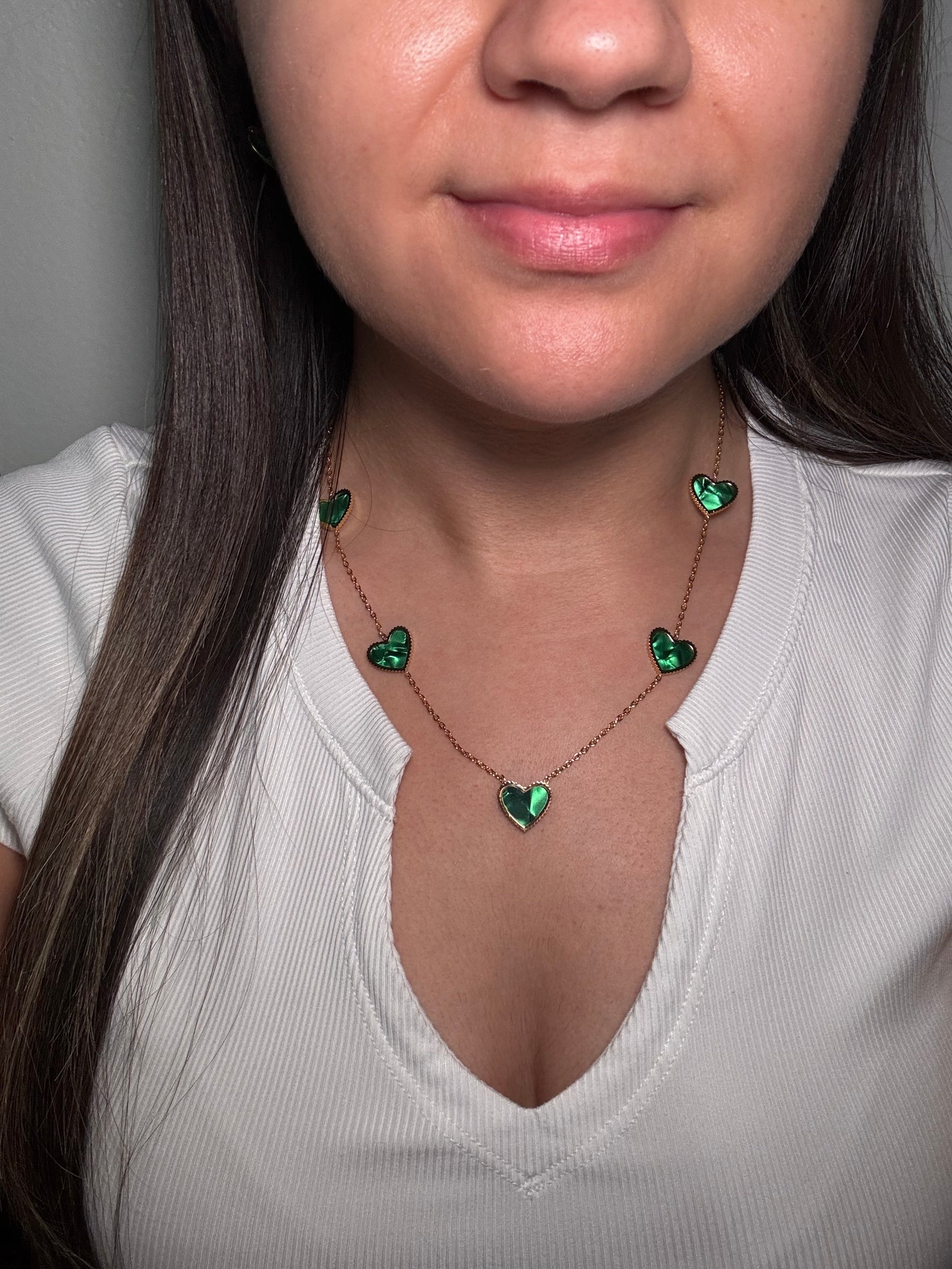 Evergreen Hearts necklace worn by model close-up showing gold chain and green heart endant at upper chest.
