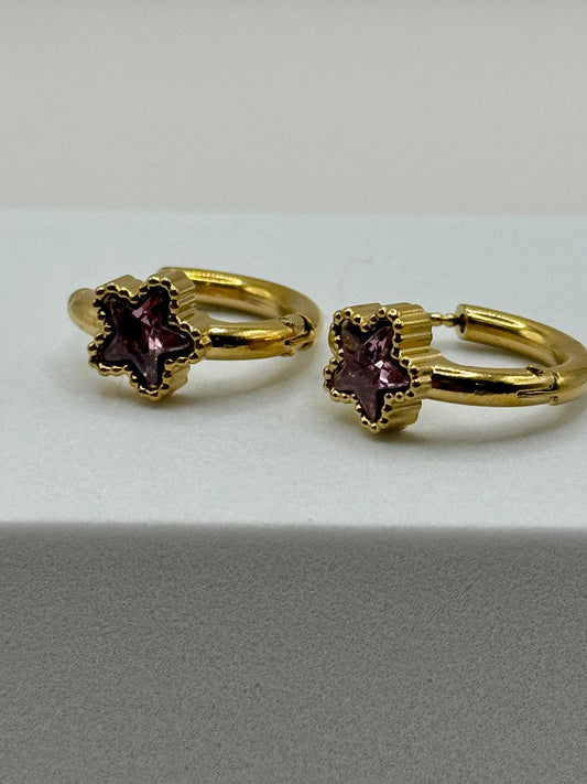 The Aubergine Hoops gold earrings with deep purple star-cut stones close-up on white background.