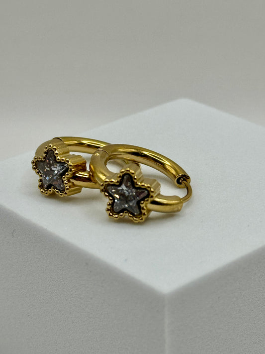 The Azure Hoops gold earrings with star-cut stones in cool silvery gray-blue, close-up on white background.