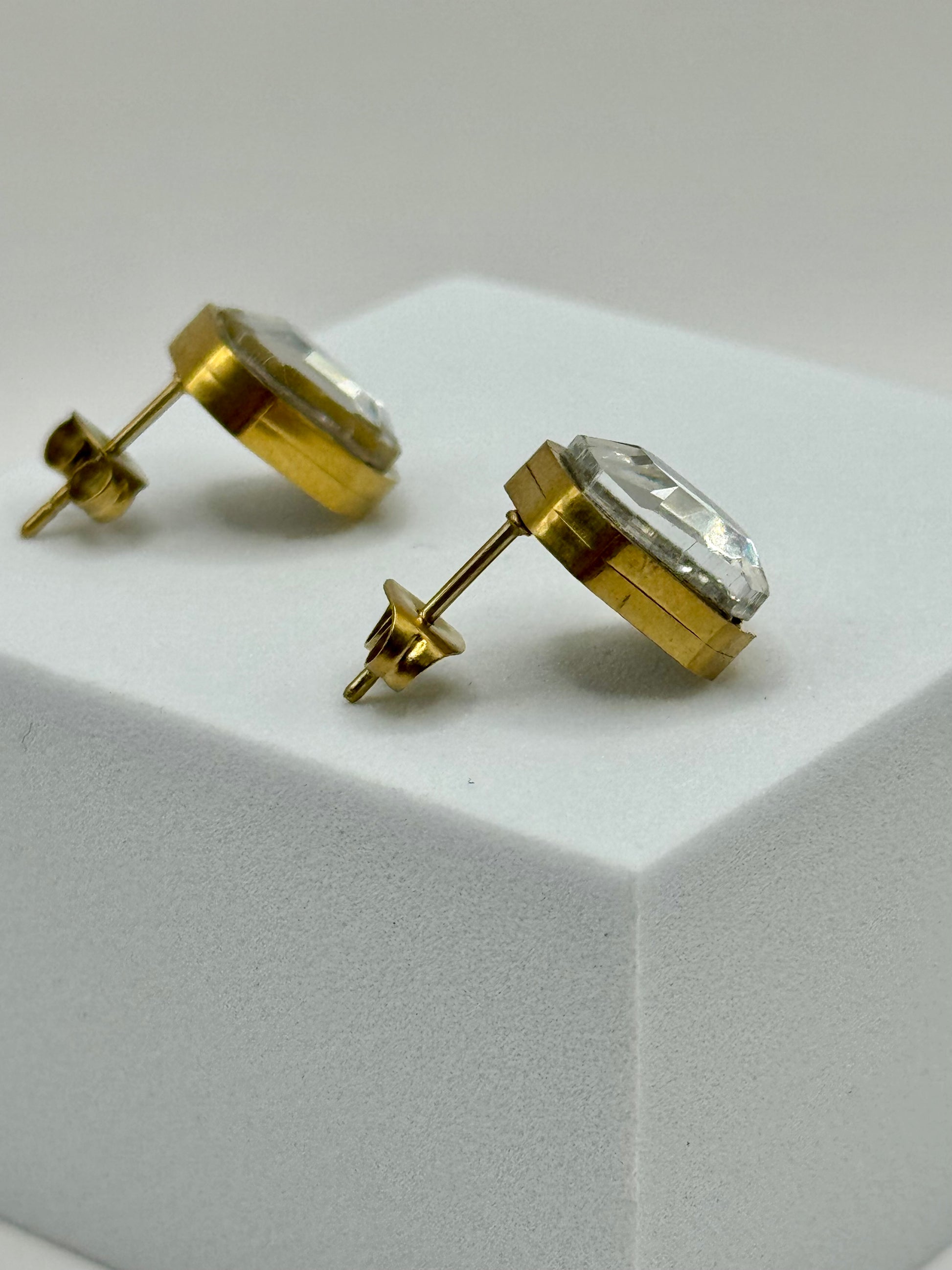 The Soleil Earrings resting on a white block, showing latch-back closure and reflective surface.