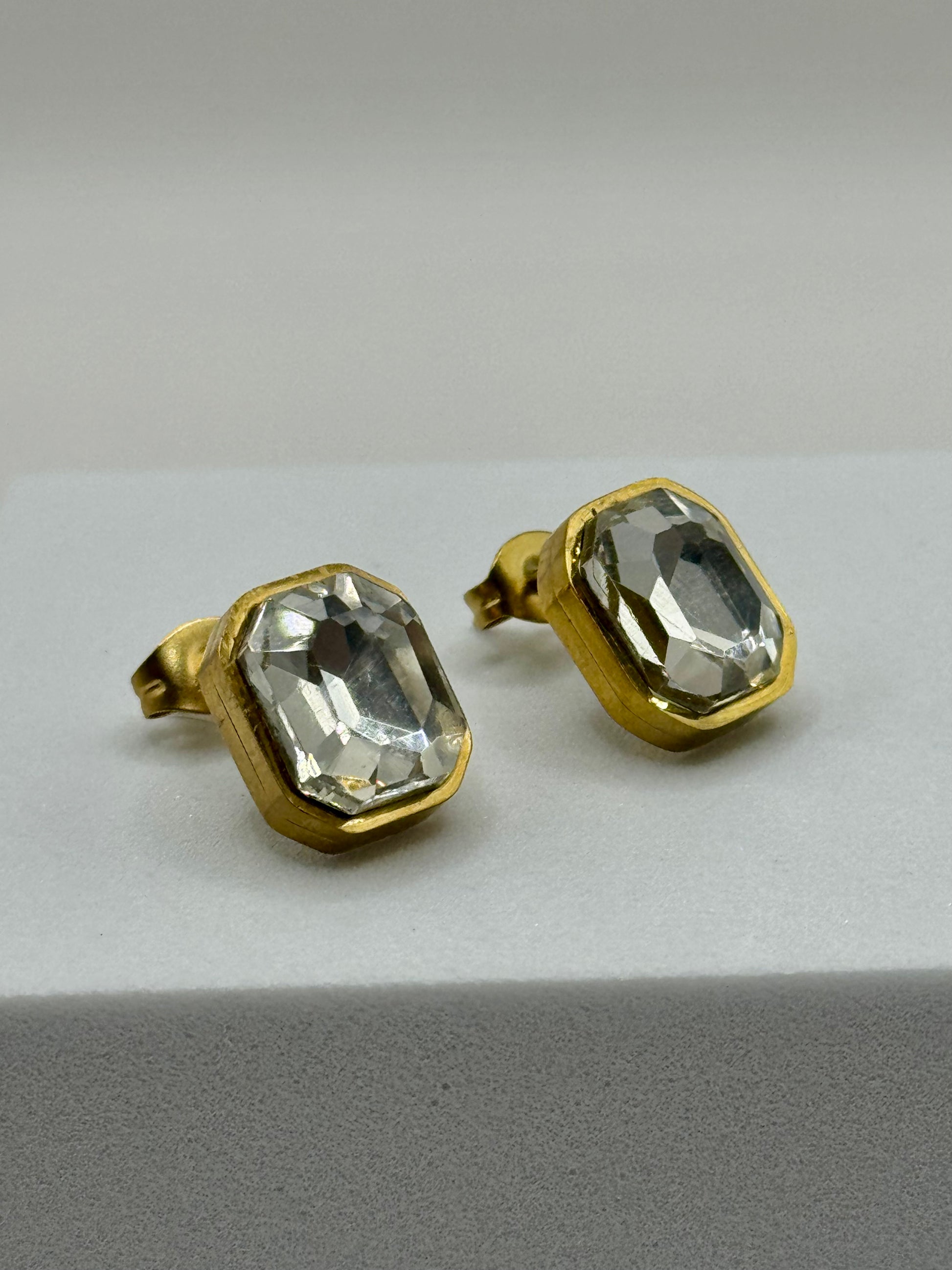 A side angle of The Soleil Earrings highlighting the golden bezel and reflective glass stones.