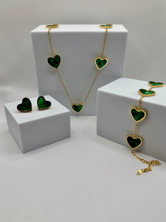 The Evergreen HEart Set complete display with necklace, bracelet, and stud earrings featuring green heart charms on white blocks.