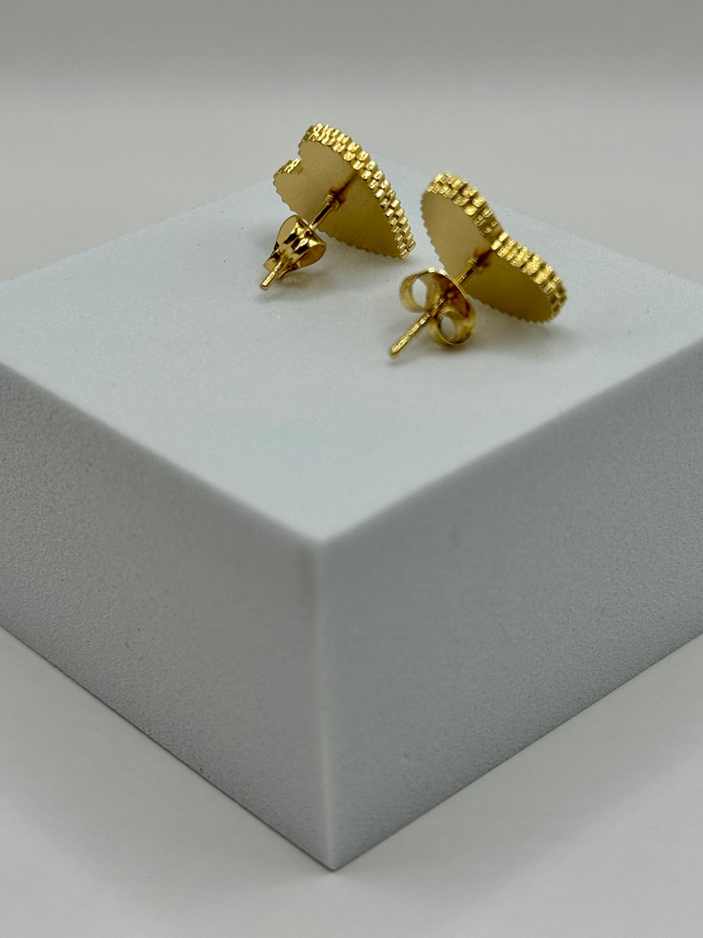 Evergreen Hearts stud earrings close-ups on white block showing polished green enamel and gold edges.