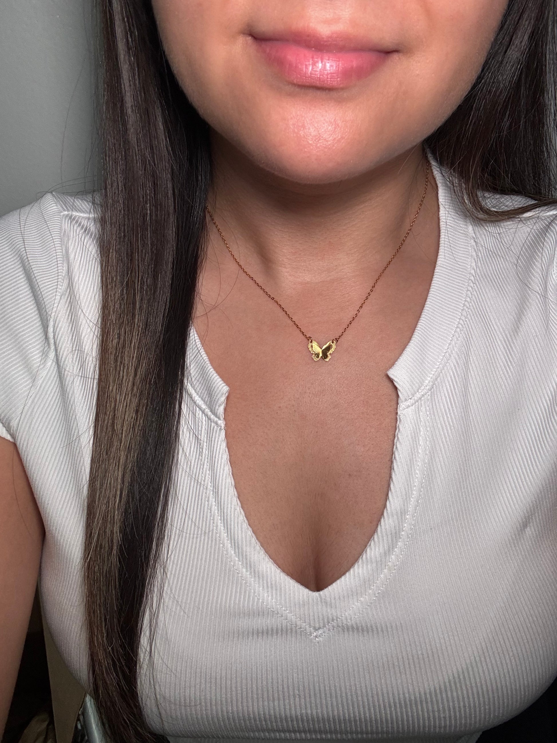 Model wearing Aurora Clásica butterfly necklace close to collarbone.