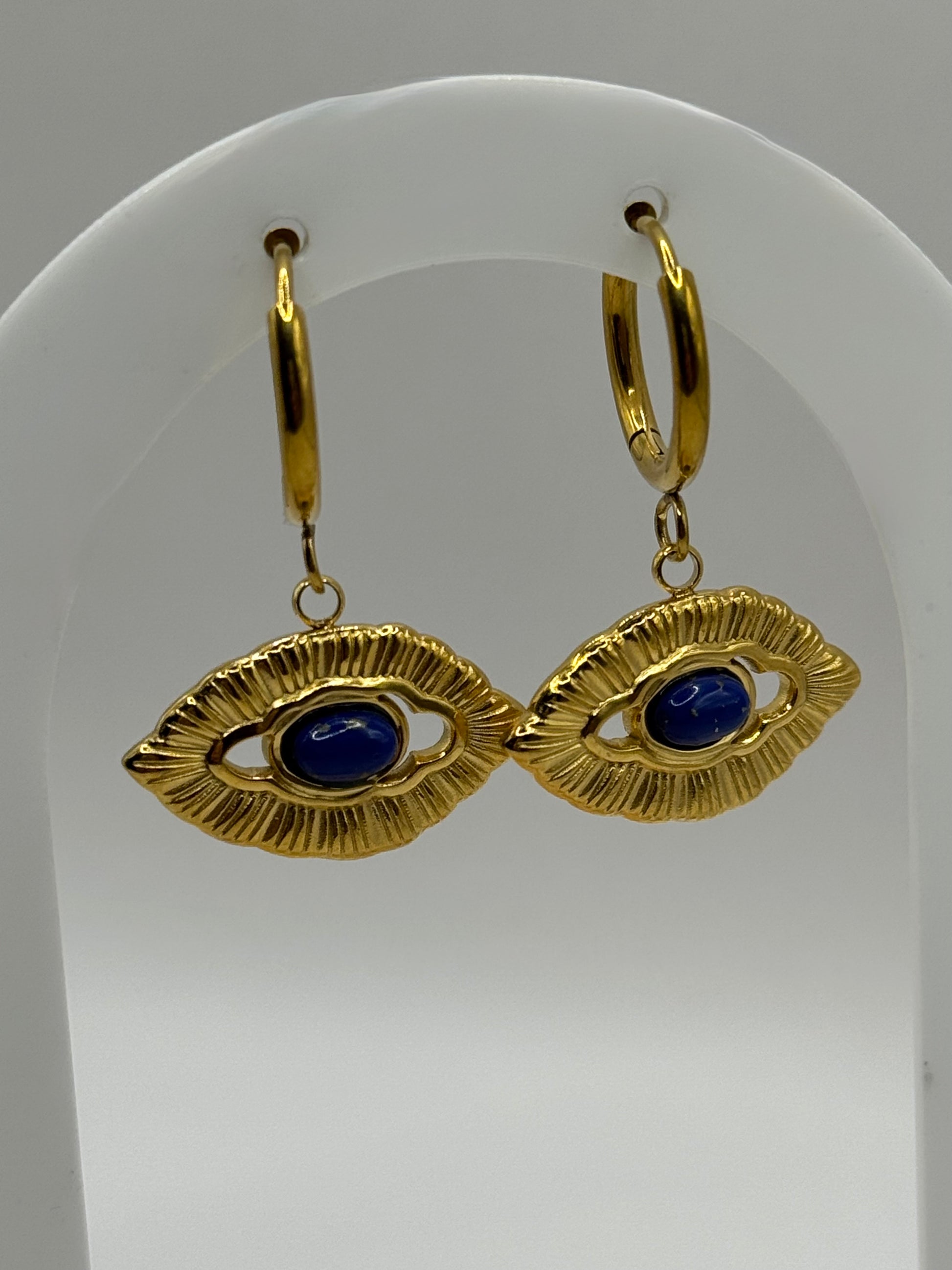 Close-up of Orovie earrings with sculpted gold frame and cobalt blue eye center.