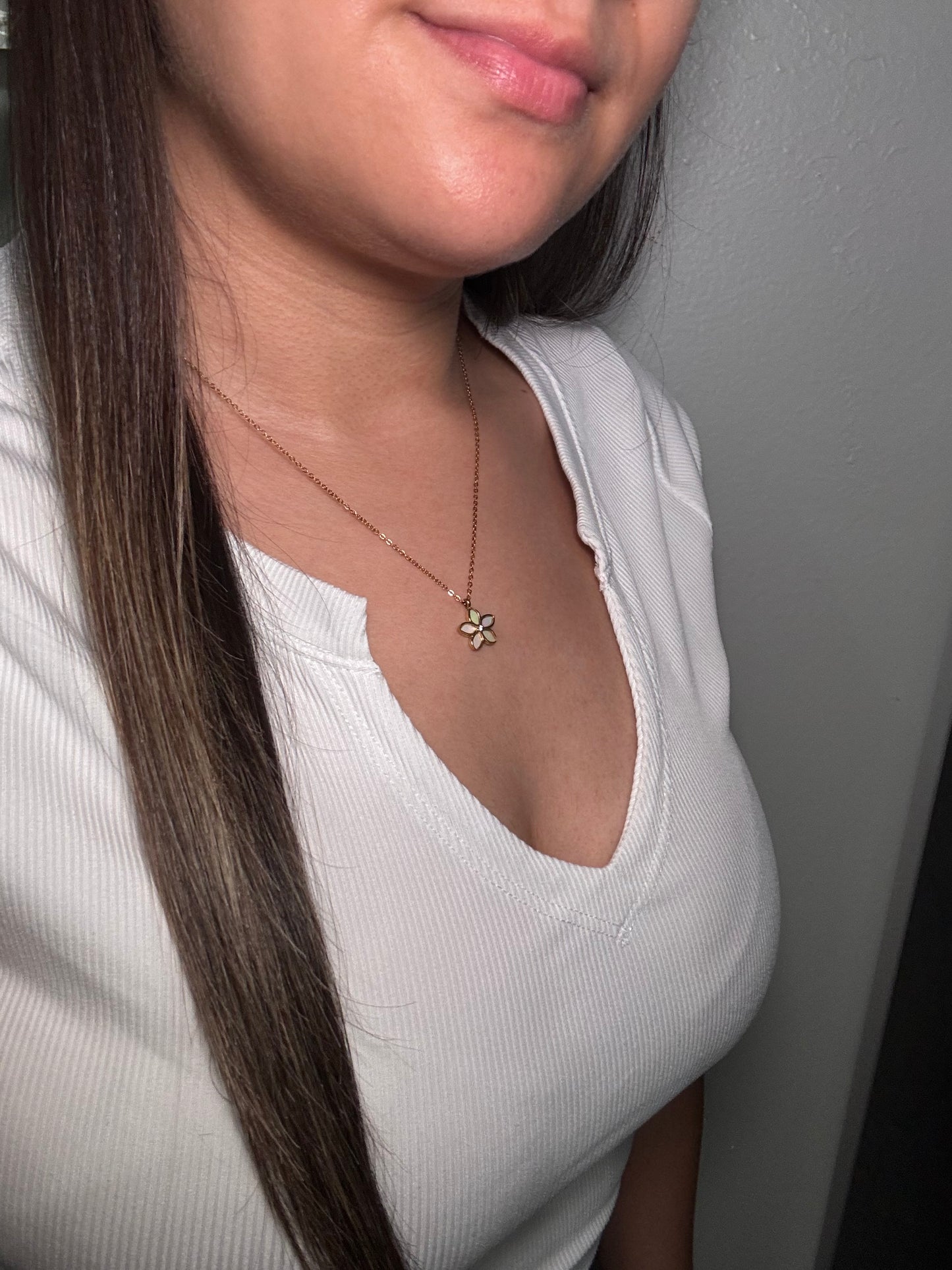 The Opalina necklace worn by model close-up lower neckline view with floral pendant resting at collarbone.