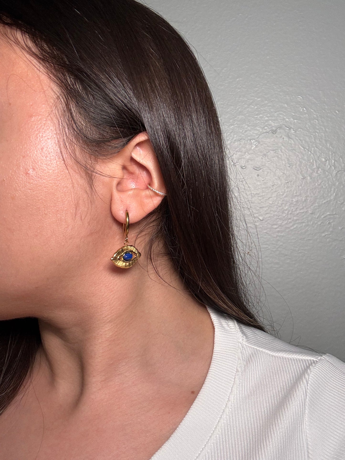 Model wearing Orovie earring, gold hoop clasp with cobalt eye detail.