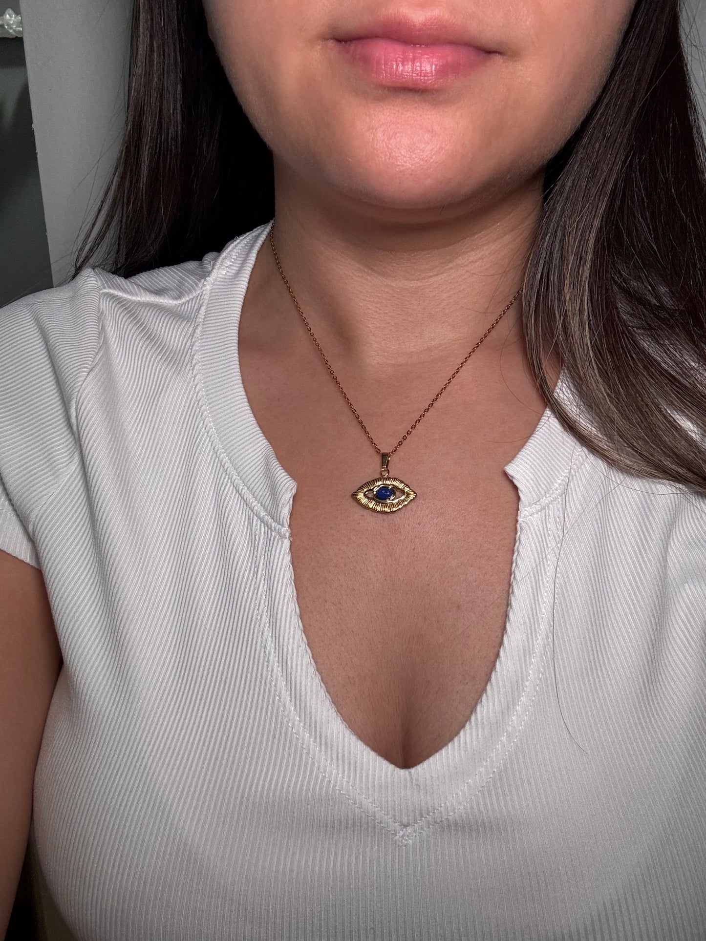 Model wearing Orovie necklace, gold and cobalt eye pendant resting at collarbone.
