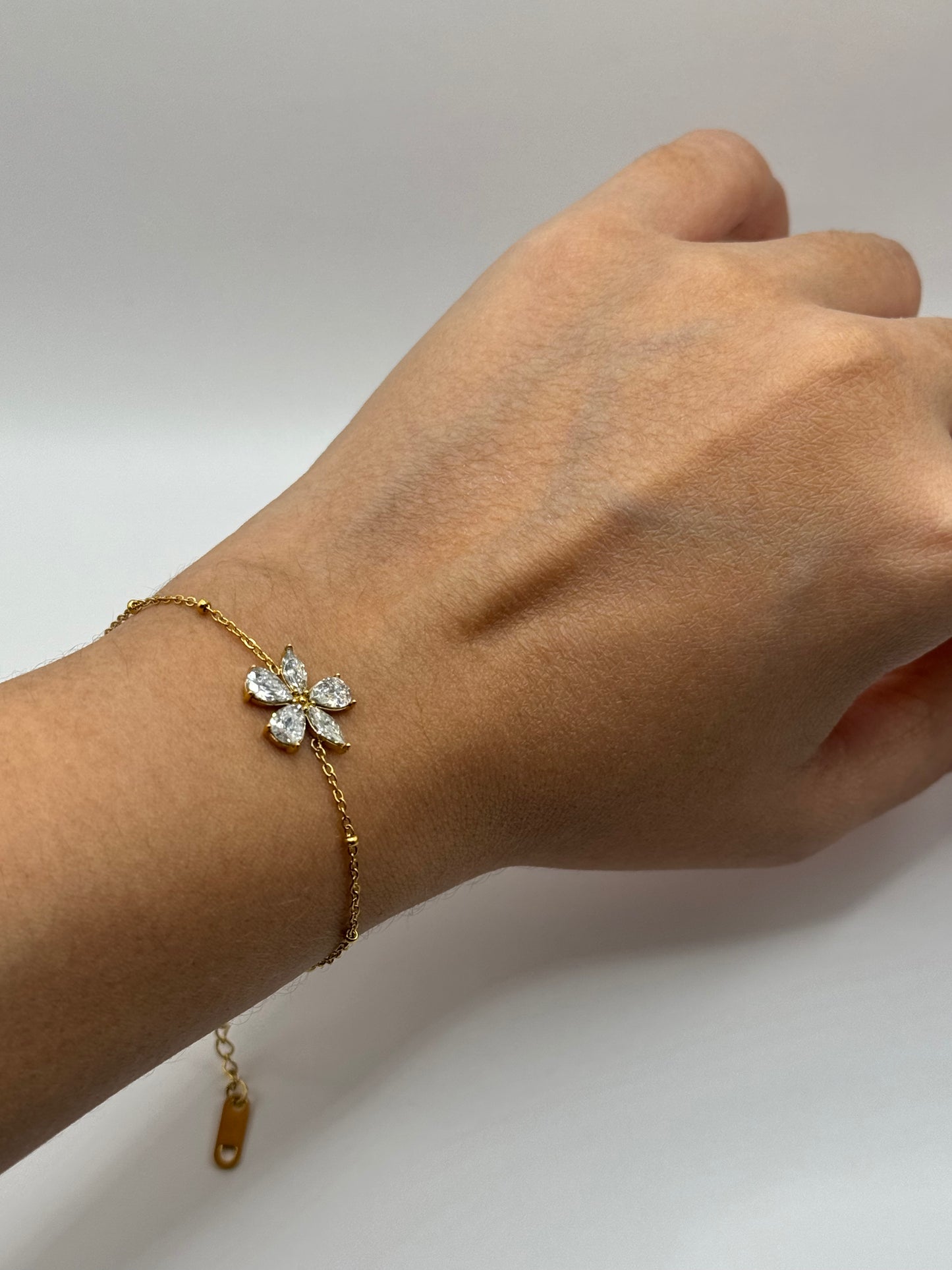 Gold double-chain bracelet with zircon flower motif worn on wrist, The Zafira Bracelet by EMPIECE™.