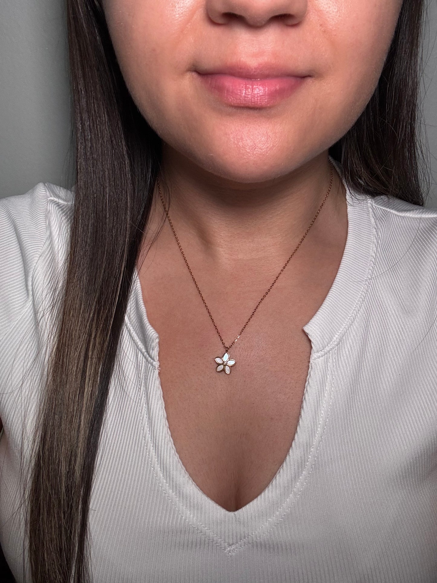 The Opalina necklace worn by model close-up on neckline showing iridescent floral pendant with gold chain.