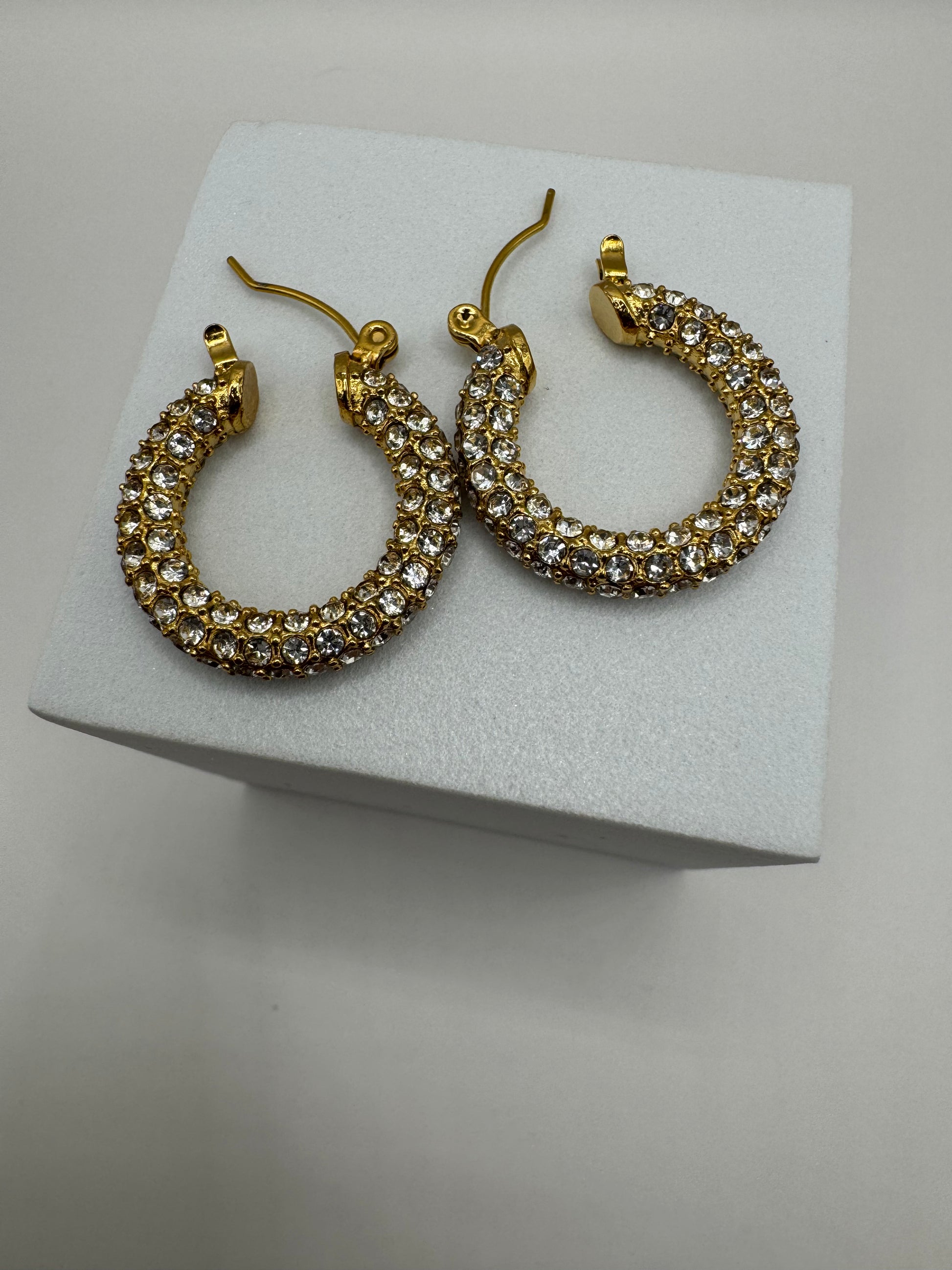 Side view of Aros Novina crystal hoops showing detailed gold-tone finish.