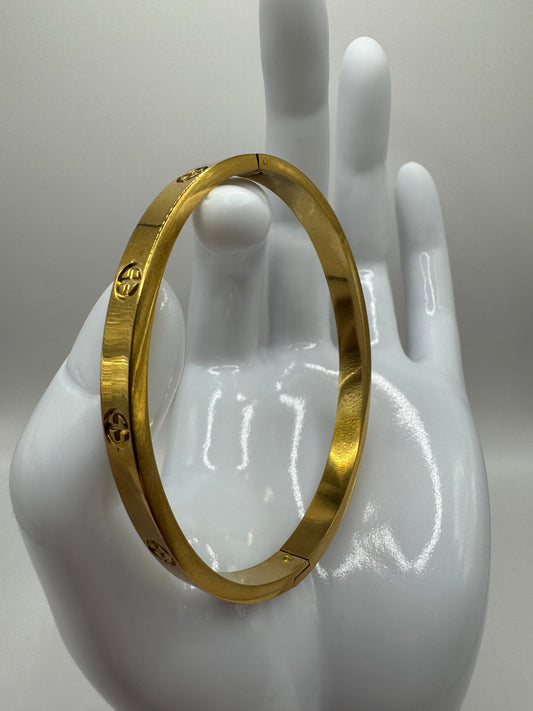 Close-up of The Eterna Bracelet displayed on a white mannequin hand, showcasing its gold-plated finish and engraved details.