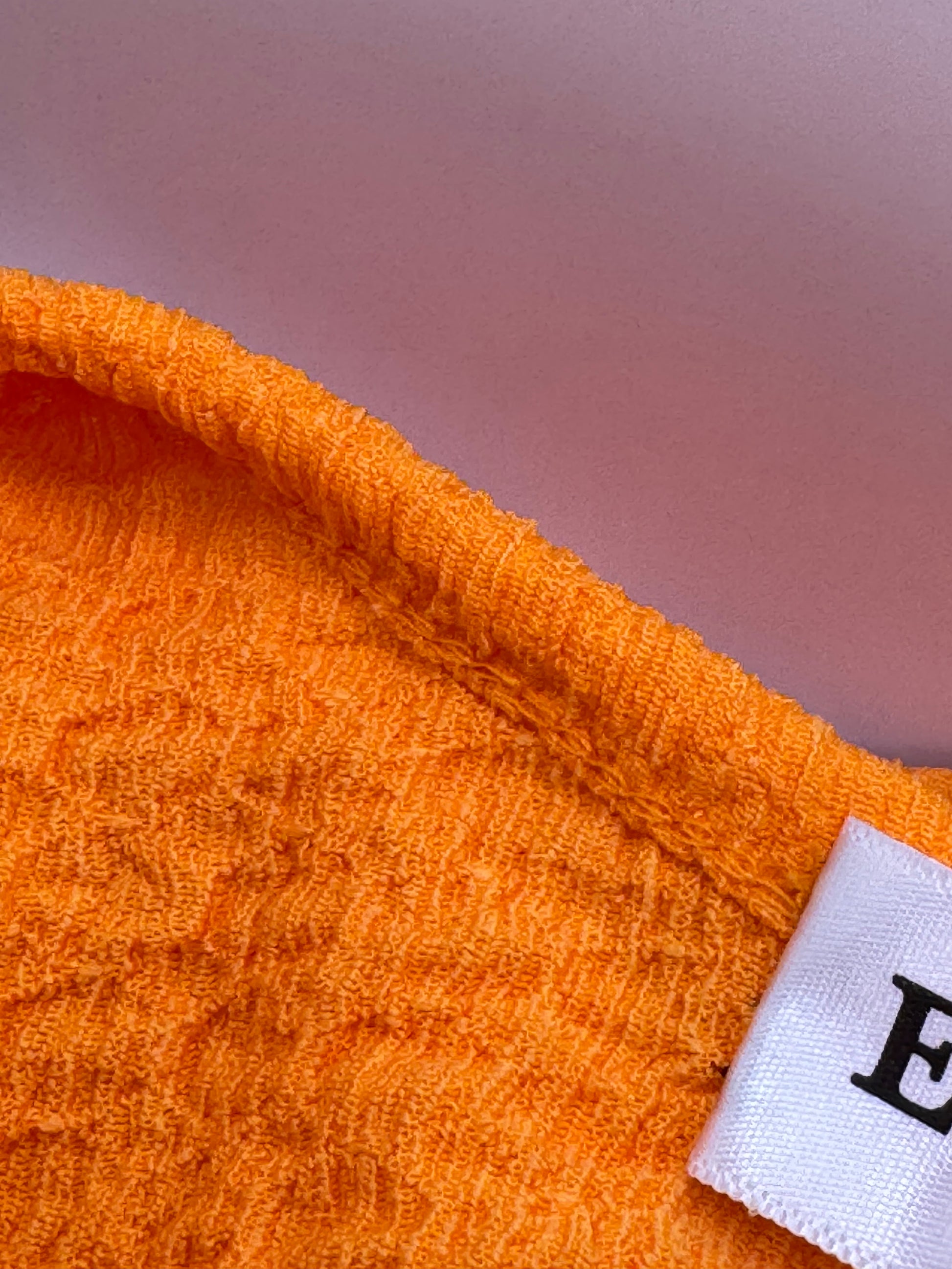 Detail of the textured orange polyester-Lycra fabric of The Scarlet Allure Top, showing its stretch and finish.