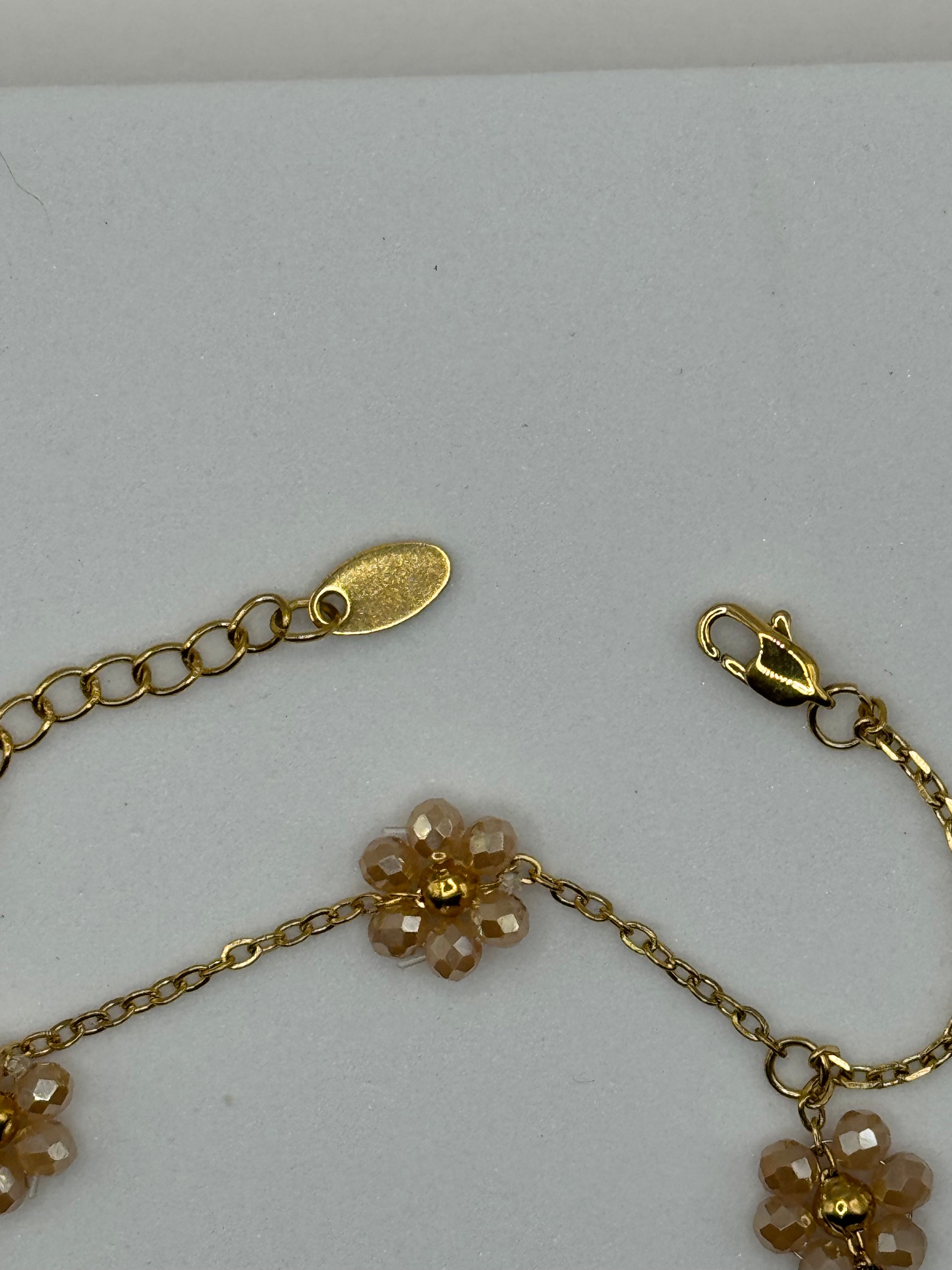 The Fleurette Bracelet displayed flat, showcasing delicate gold floral links and adjustable chain extension.