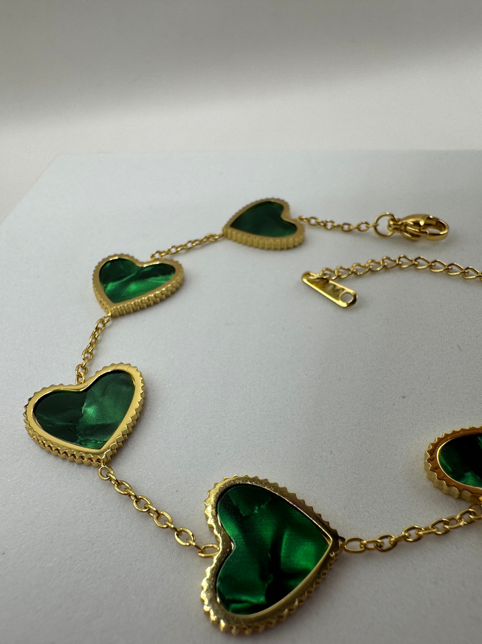 Evergreen Hearts bracelet with multiple green heart charms displayed flat on white surface showing chain detail.