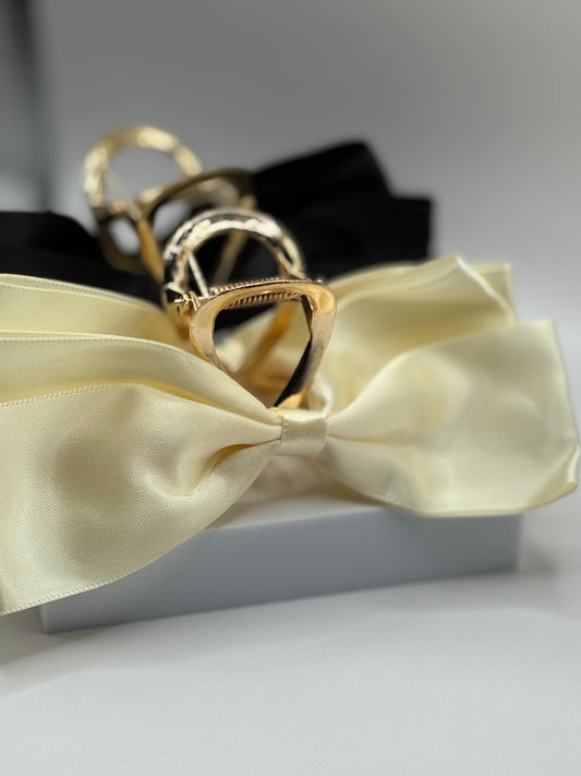 Close-up of EMPIECE™ Paloma Hair Clip in ivory satin with gold claw detail on white block.