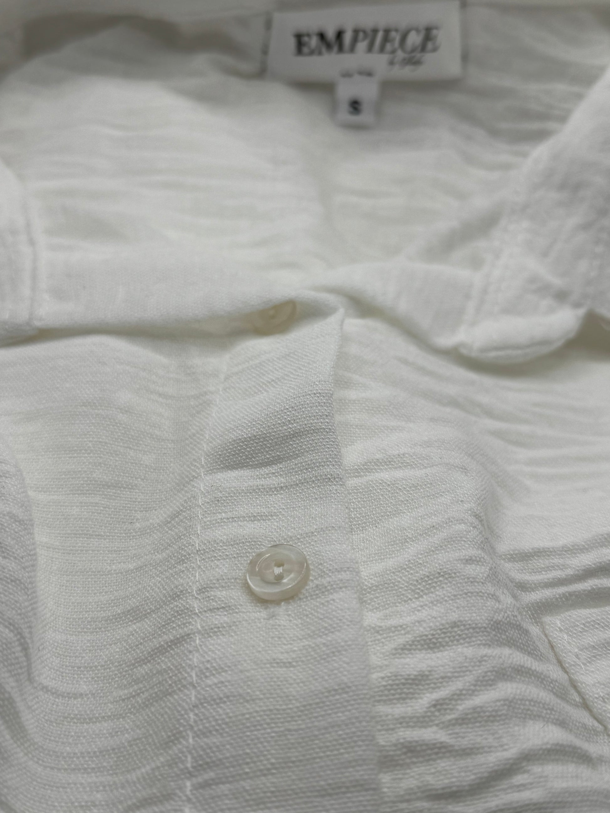 Detail of front button placket on The Clarity Whisper Top, highlighting its textured white viscose-linen fabric.