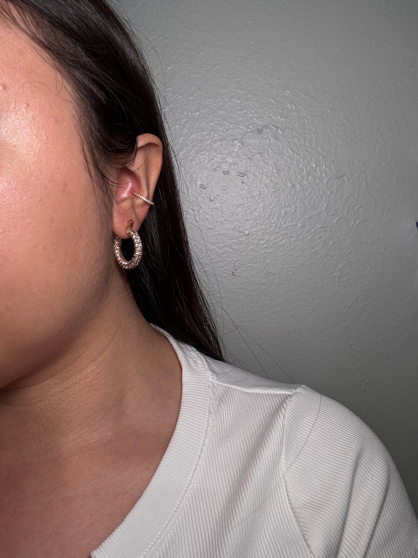 Model wearing Aros Novia crystal hoop earrings styled with white top.