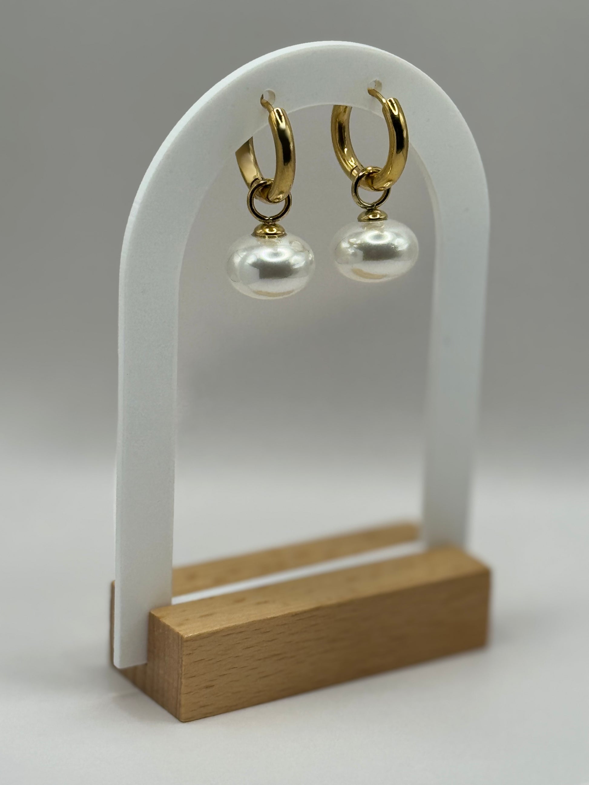 The Petaluna Earrings displayed on a stand, gold floral motif with pearl accents.