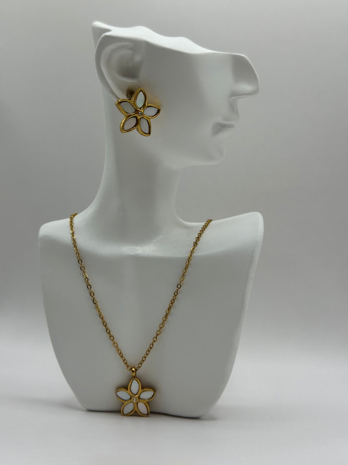 The Opalina necklace and stud earrings displayed upright on white jewelry stand showing floral enamel design.