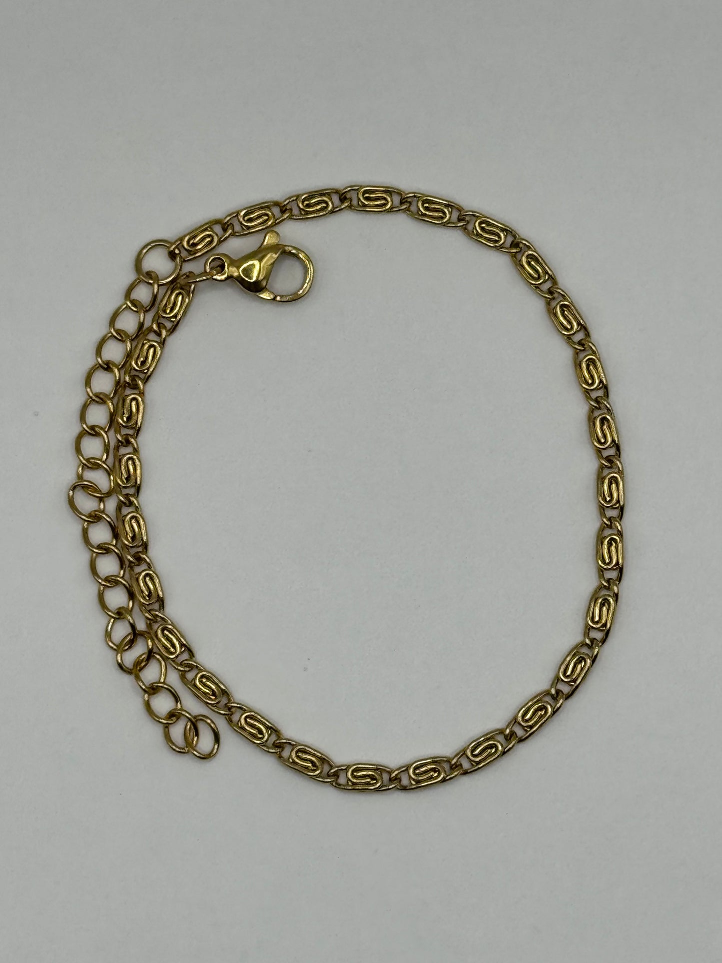 Amélie Bracelet laid flat, polished gold-tone geometric links with subtle shine.