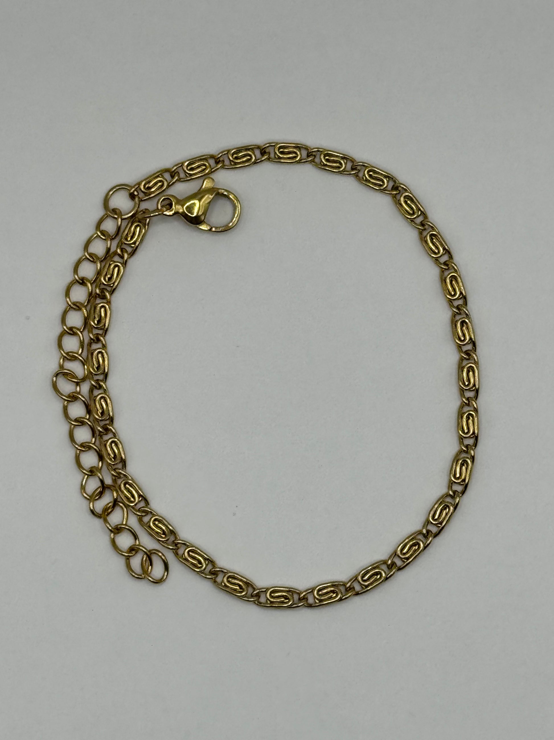 Amélie Bracelet laid flat, polished gold-tone geometric links with subtle shine.