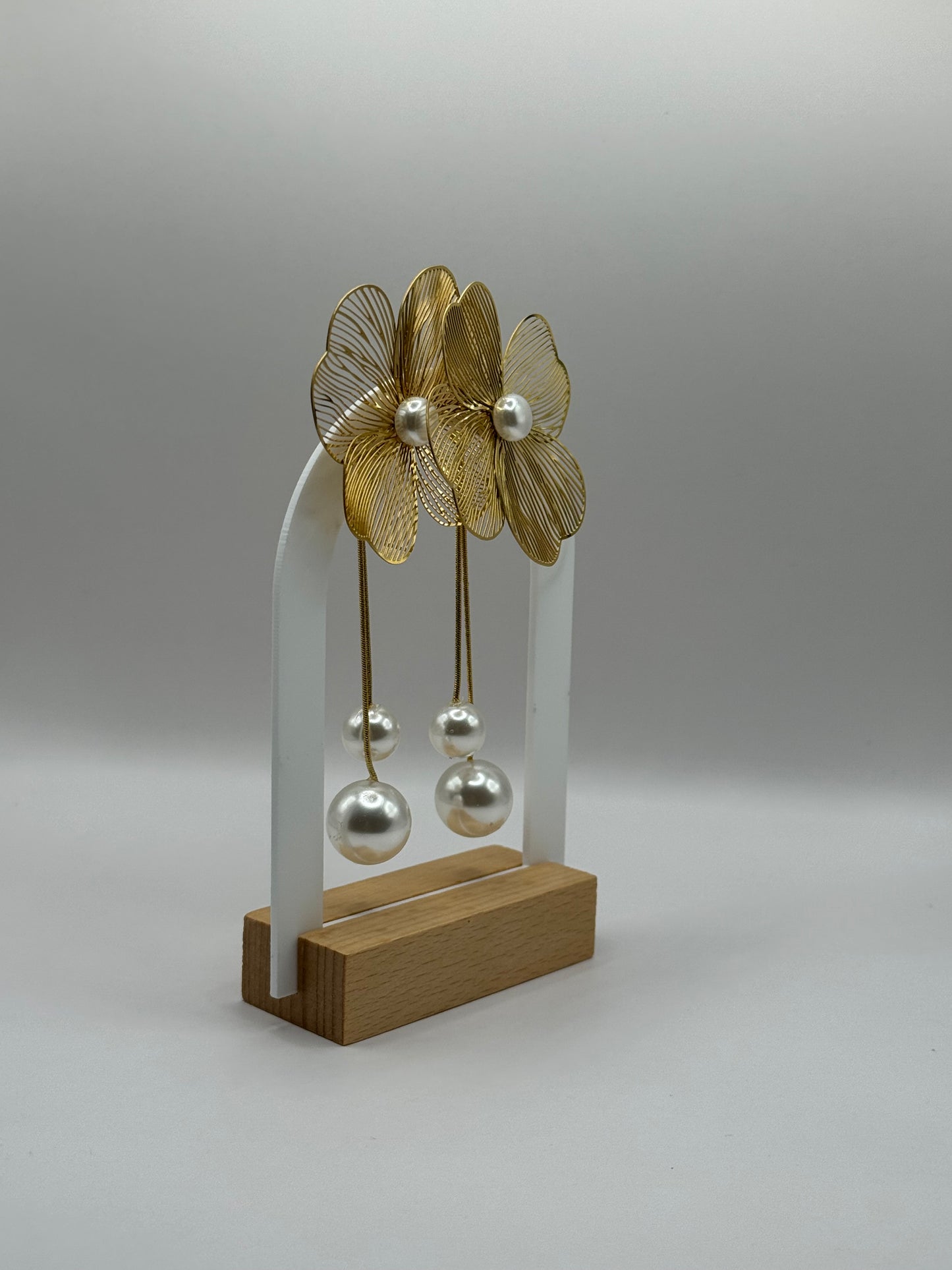 The Nerina Earrings displayed on jewelry stand showing gold-plated flower design with pearl accents.