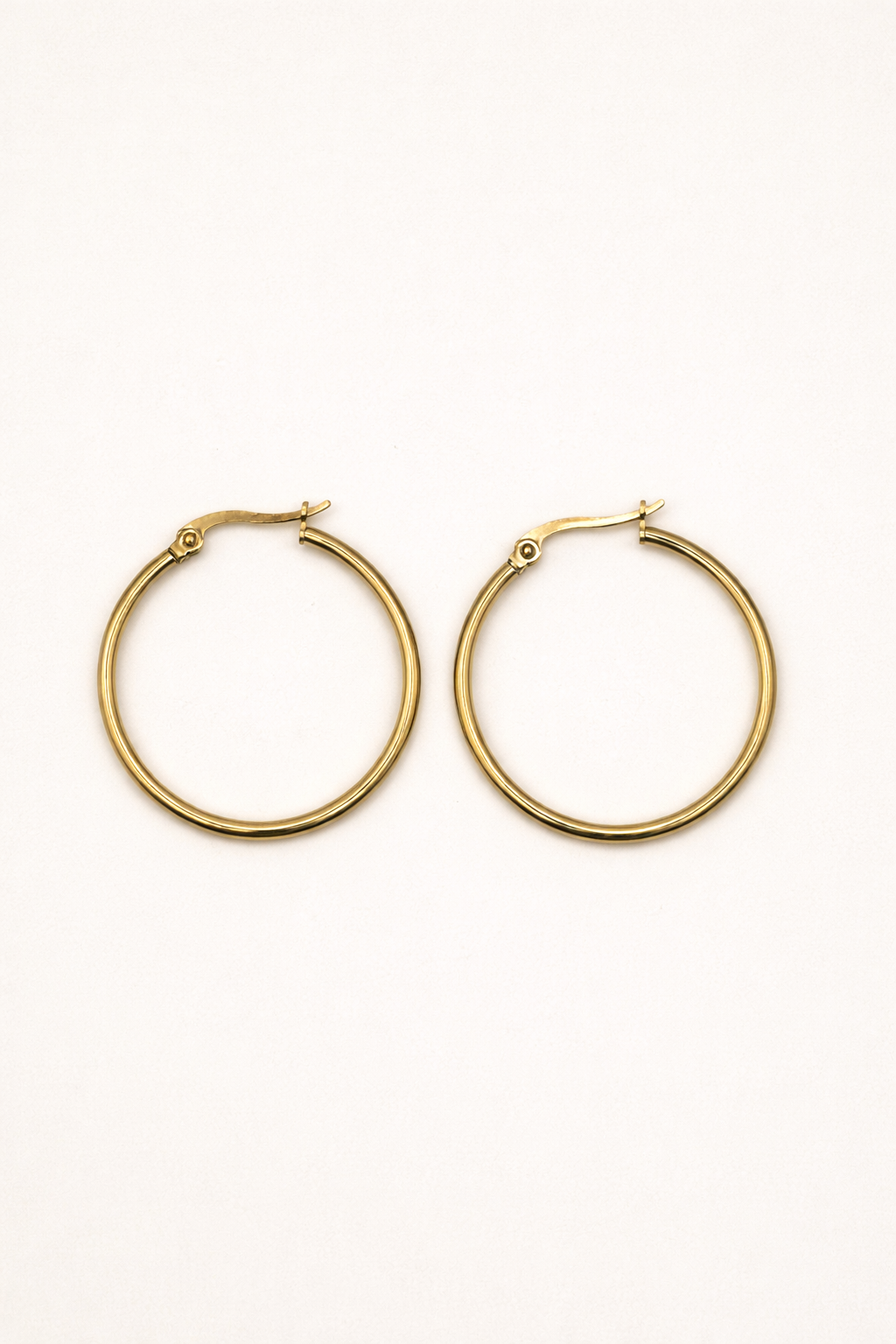 Gold hoop earrings with a smooth rounded silhouette on a white background