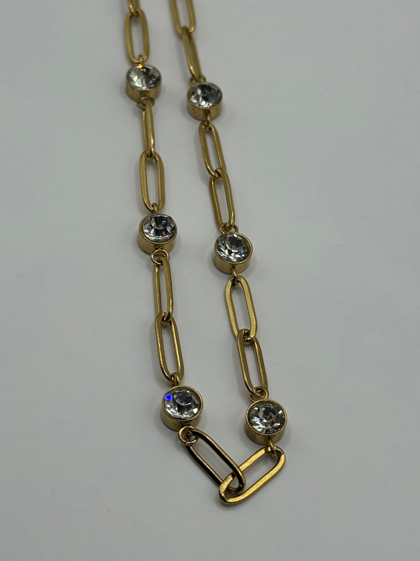 EMPIECE™ The Adelaide Necklace detail showing gold paperclip links with clear crystal accents and toggle-style clasp on a neutral background.