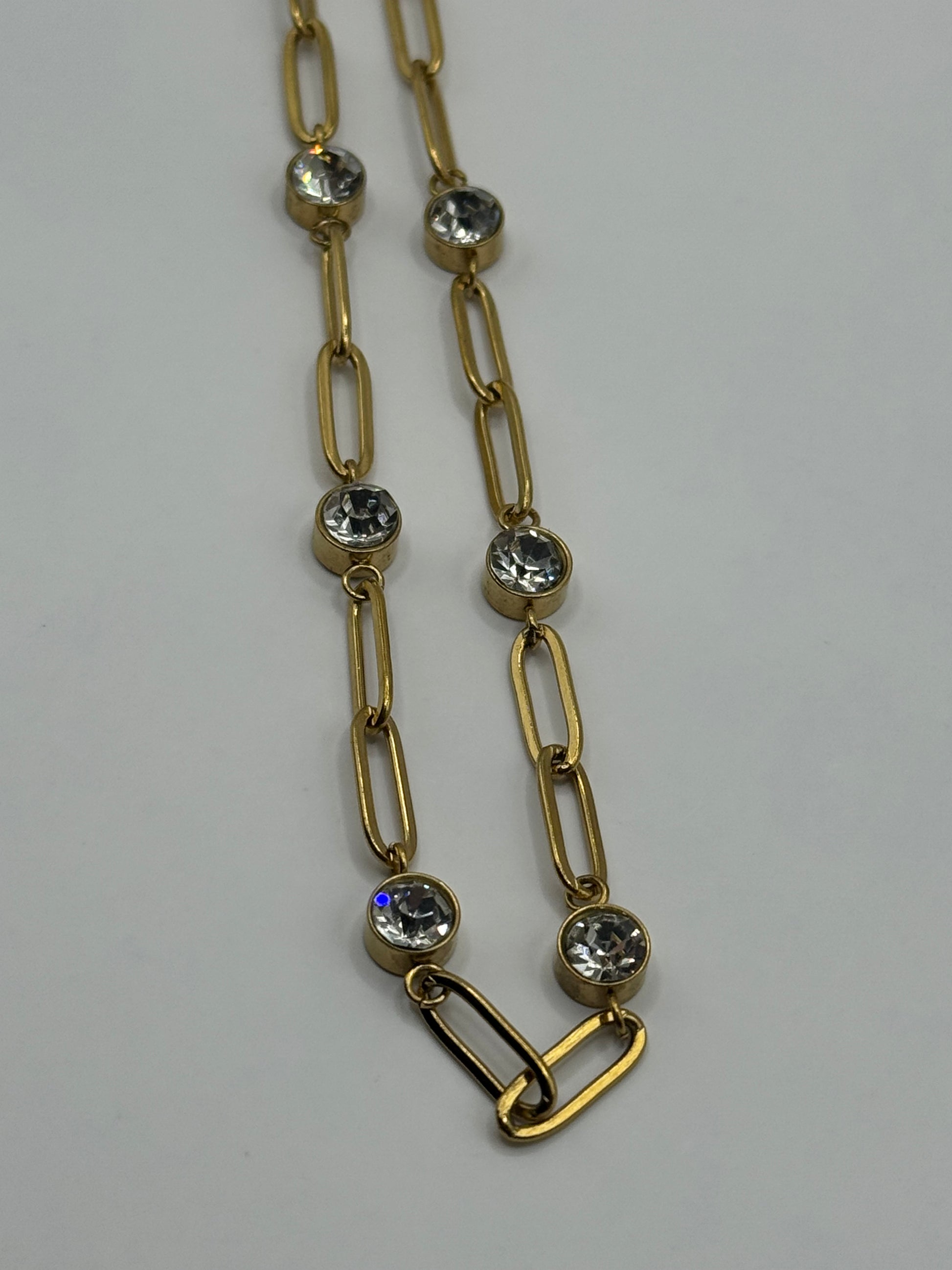 EMPIECE™ The Adelaide Necklace detail showing gold paperclip links with clear crystal accents and toggle-style clasp on a neutral background.