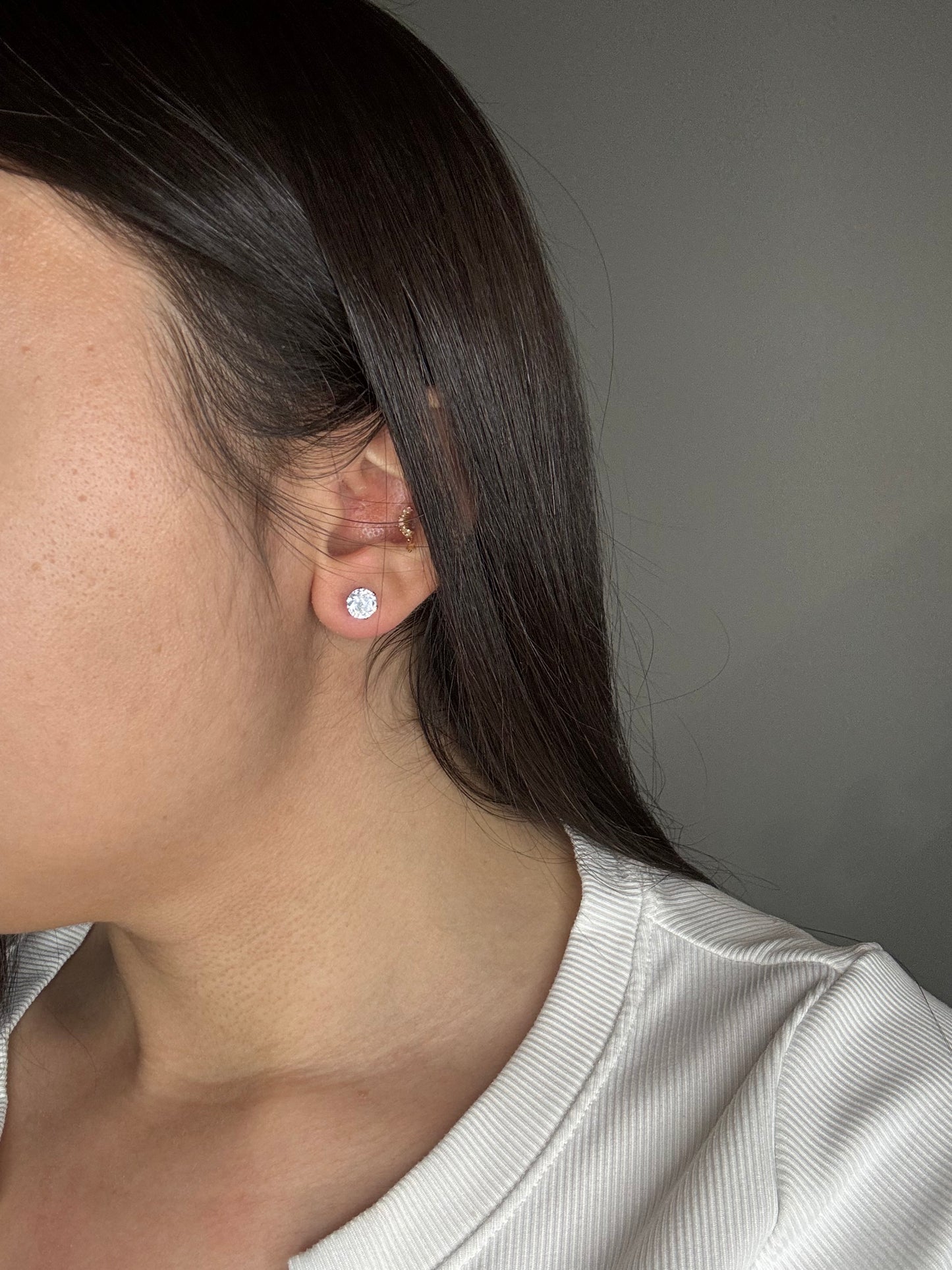 Silver cubic zirconia stud earrings worn on ear, The Ari Studs by EMPIECE™.