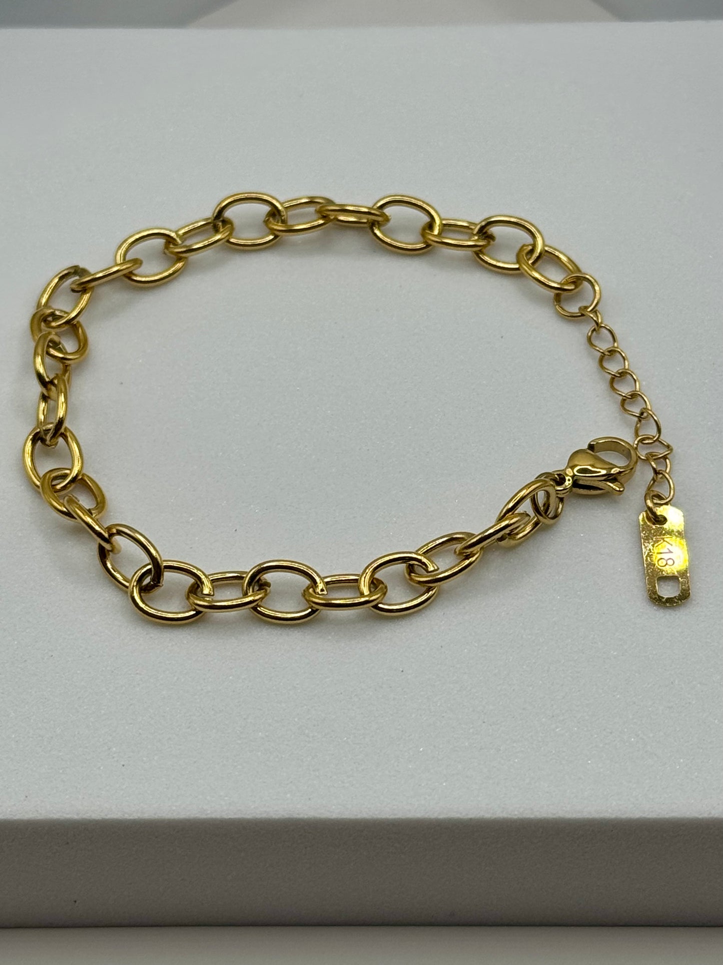 Gold chain bracelet with oval links and lobster clasp laid flat on a white block, The Rowan Bracelet by EMPIECE™