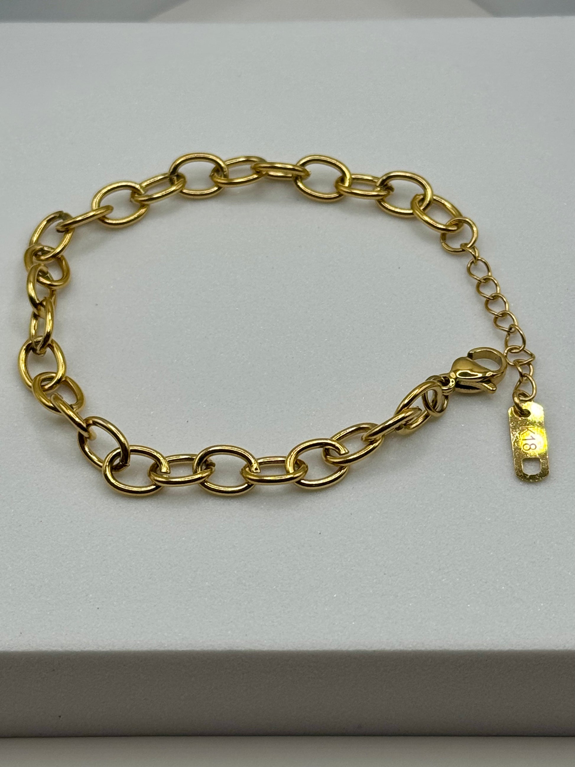 Gold chain bracelet with oval links and lobster clasp laid flat on a white block, The Rowan Bracelet by EMPIECE™
