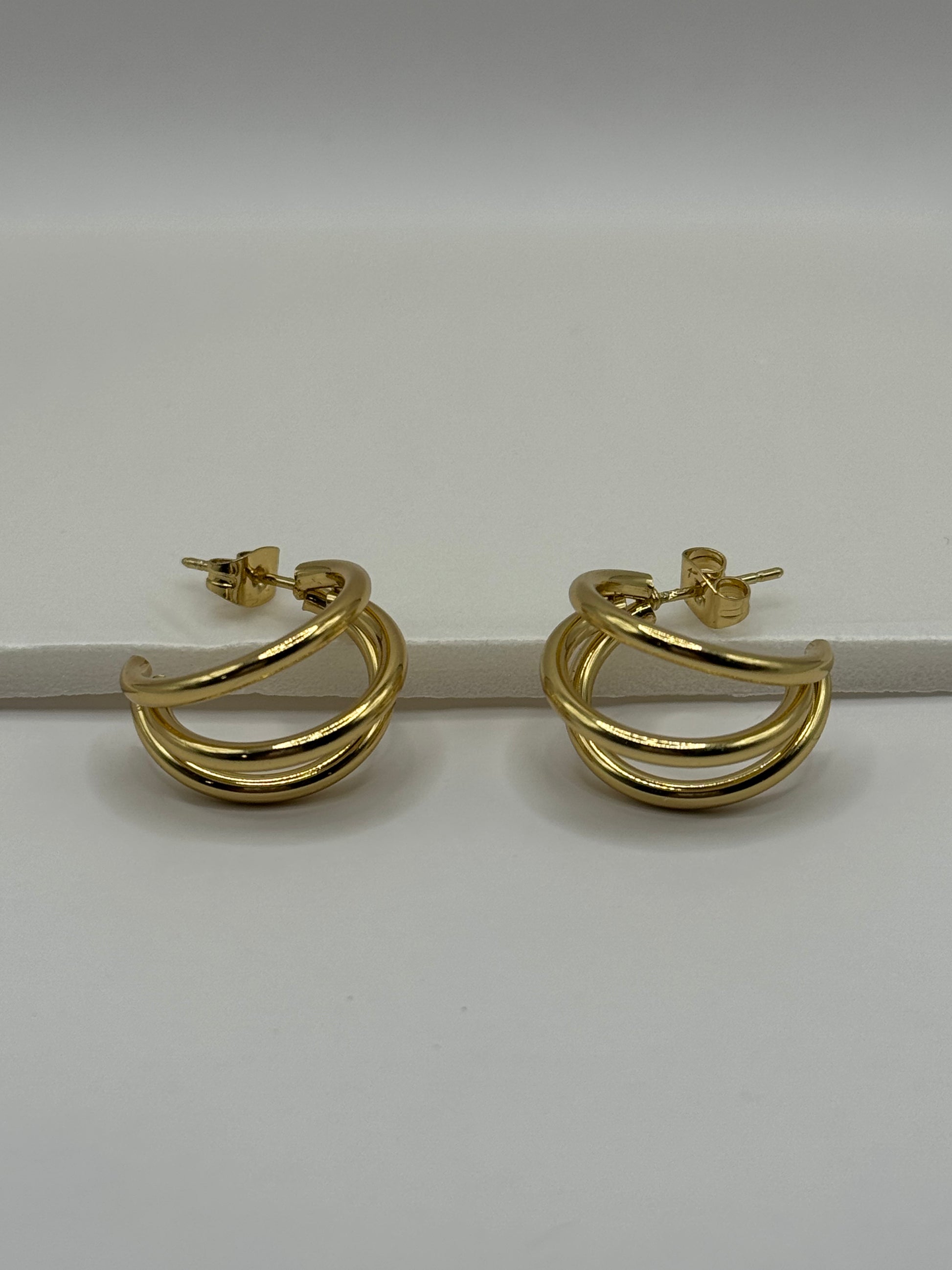 Gold stacked huggie hoop earrings with double-band design, photographed from the side on a neutral background
