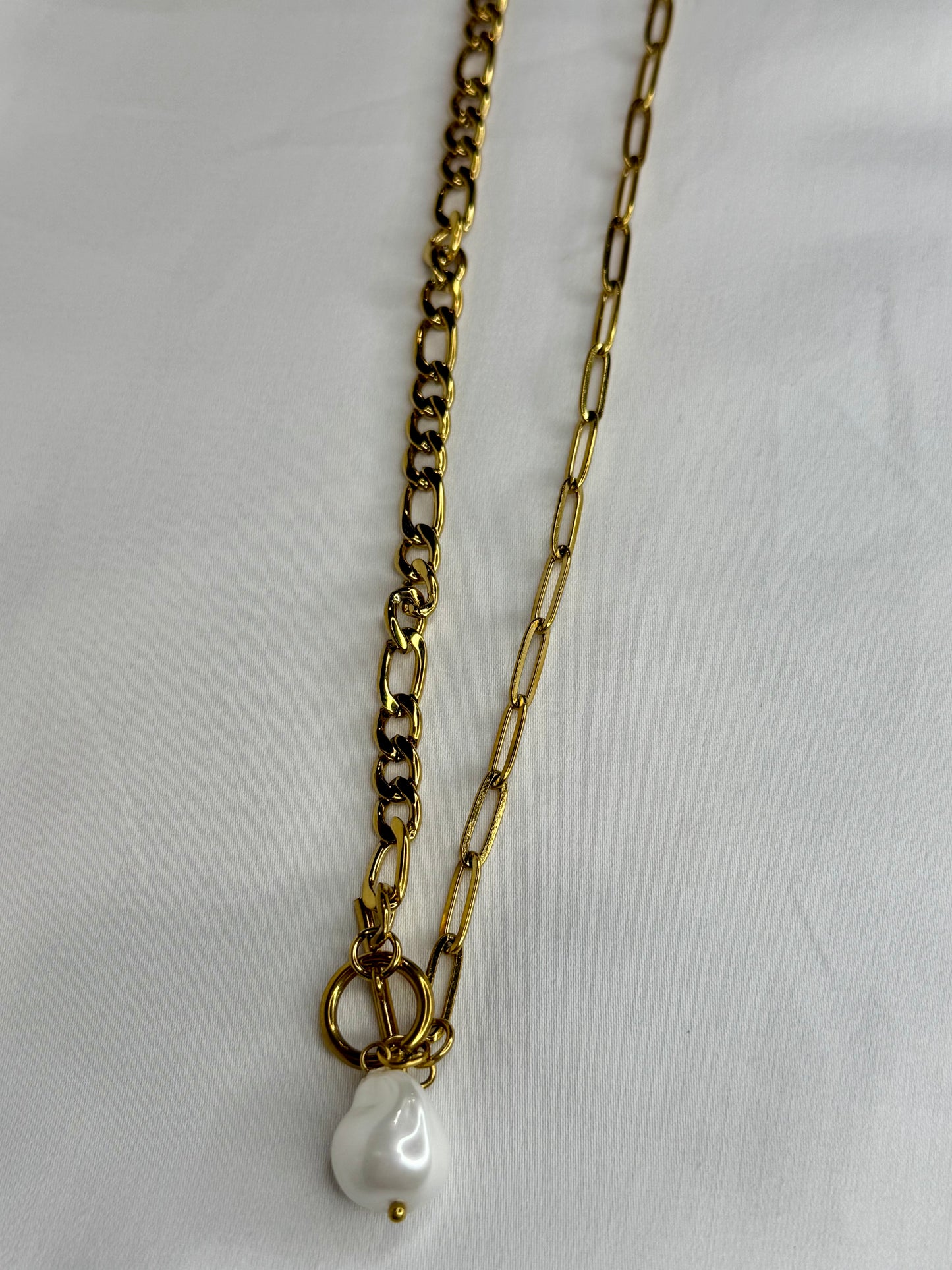 The Perla Necklace by EMPIECE™, featuring a layered gold chain design with a luminous pearl drop and toggle clasp detail.