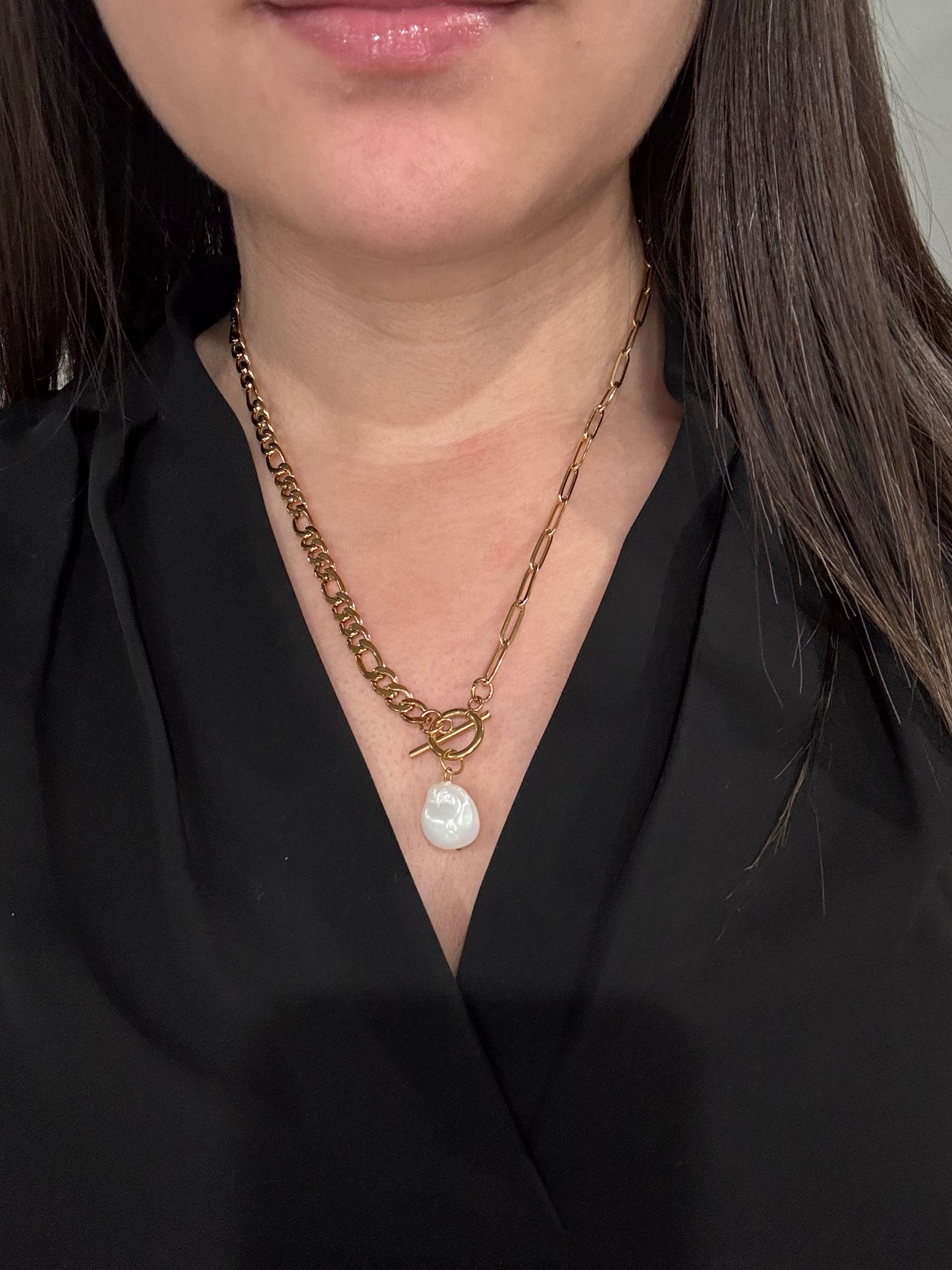 The Perla Necklace by EMPIECE™, shown worn on a model, featuring a layered gold chain with a pearl drop and toggle clasp.
